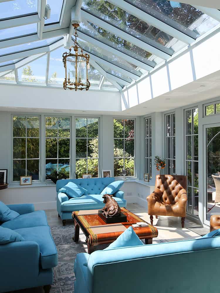 Amersham orangery living room with blue sofas beneath a glazed roof lantern