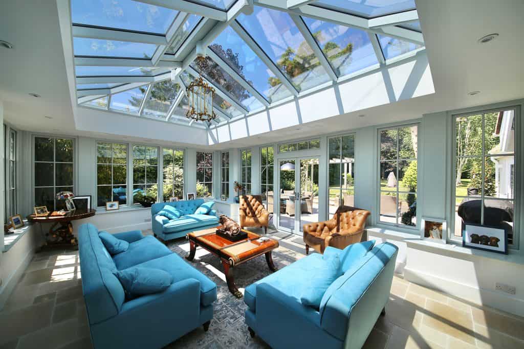 Sunlit orangery interior with blue sofas, armchairs and roof lantern