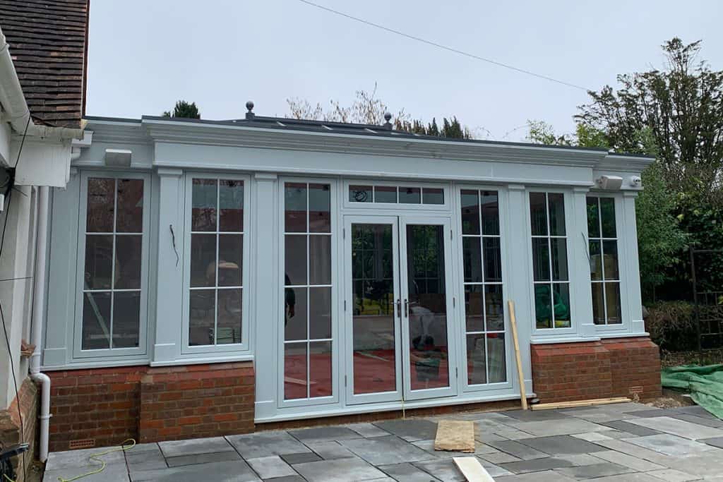 Painted orangery doors and windows beside the new patio during finishing