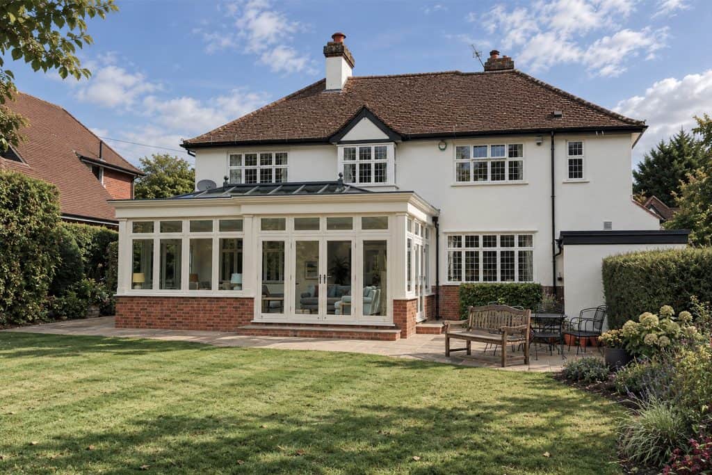Finished Harpenden orangery viewed from the garden, with French doors and a brick base