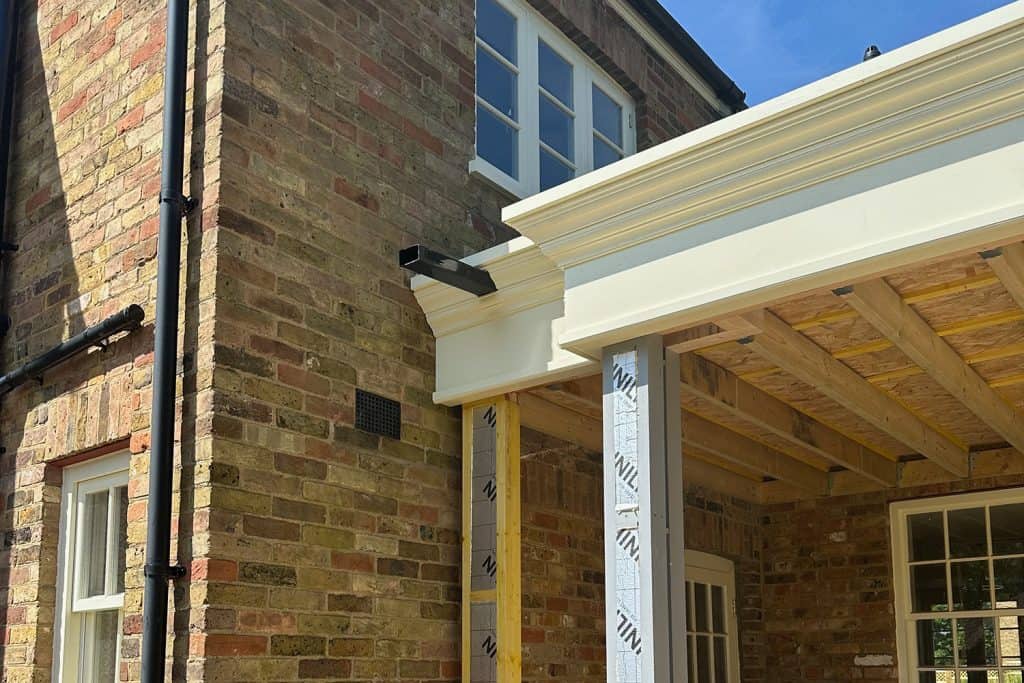 Timber roof structure and decorative fascia being fitted against the brick house
