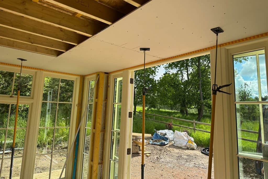 Plasterboard being fixed to the garden room ceiling above the glazed doors