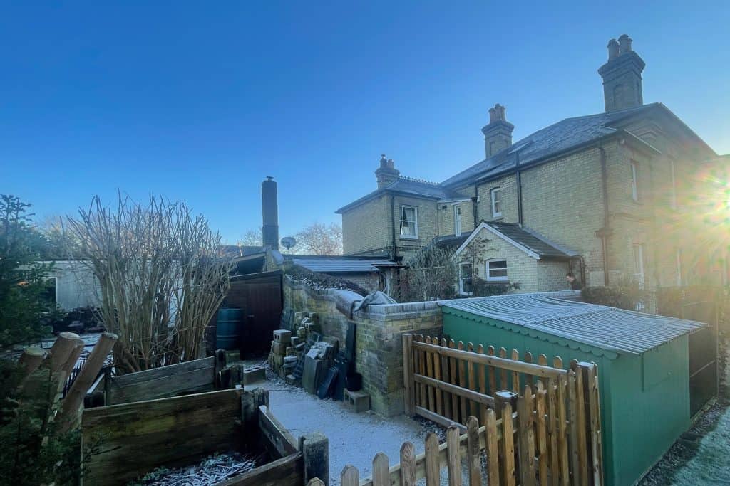 Unused rear garden corner with outbuildings and mismatched roofs before the orangery build