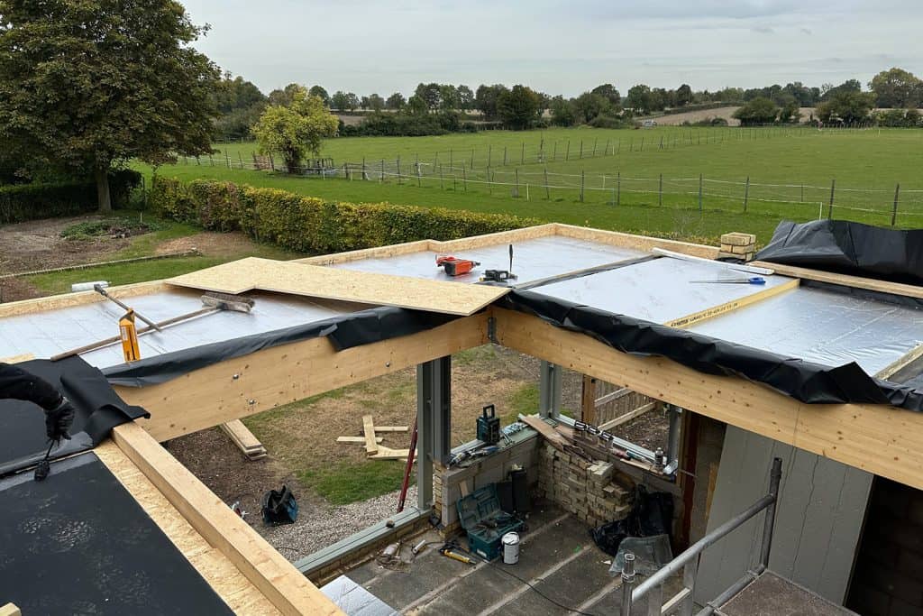 Glulam beams and warm-deck roof under construction, with open countryside beyond