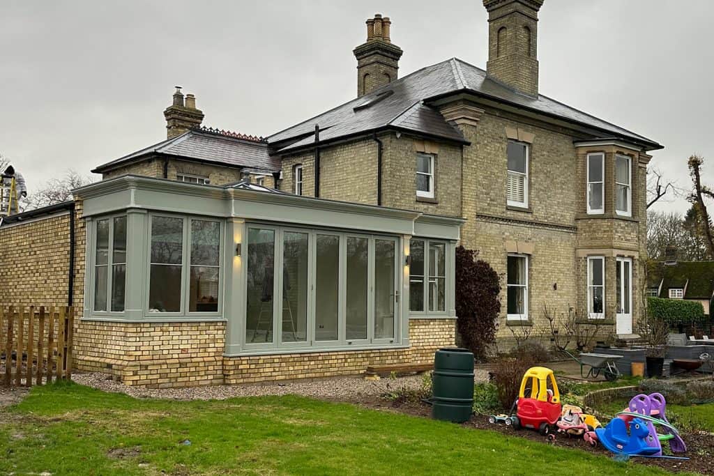 Pastel-green orangery beside the Victorian villa before the garden was landscaped