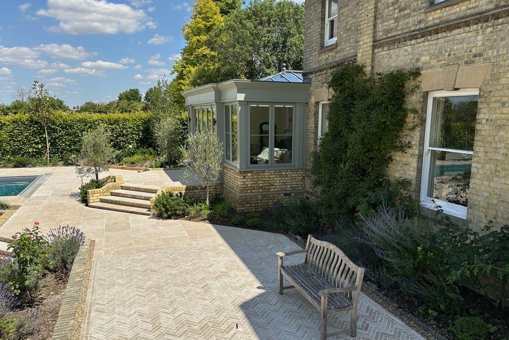 Pastel-green orangery and patio beside the landscaped garden