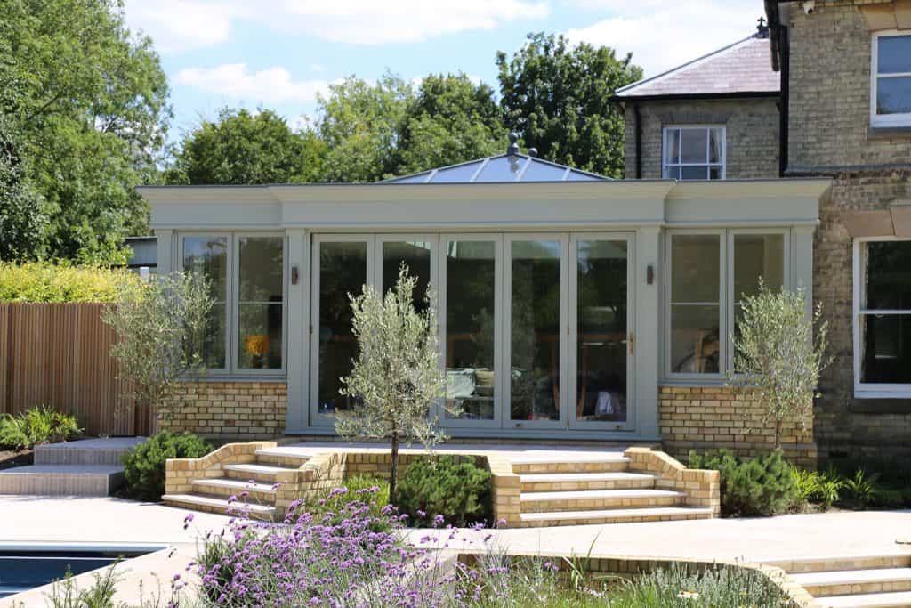 Pastel-green orangery with bifold doors opening onto the patio