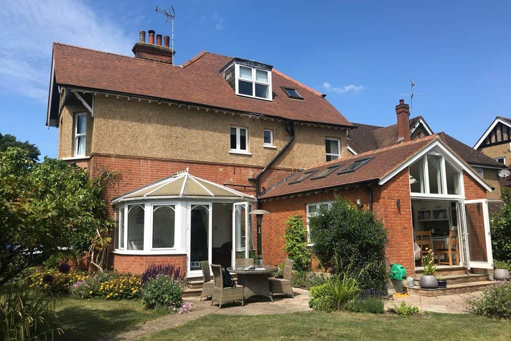 Original St Albans house with a small hexagonal uPVC conservatory beside a brick extension