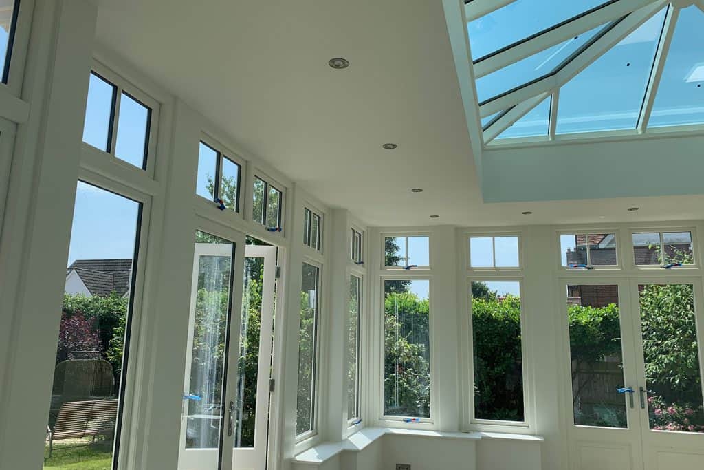 Painted orangery interior with tall windows, double doors and a roof lantern