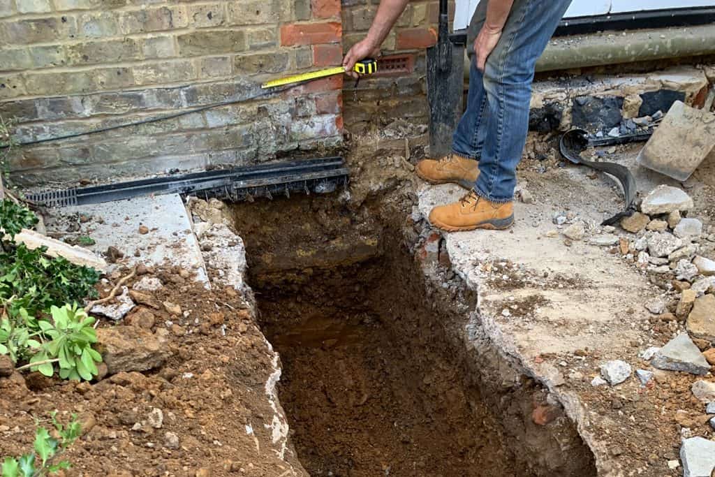 Trial hole dug beside the existing brick wall to assess ground conditions for the foundations