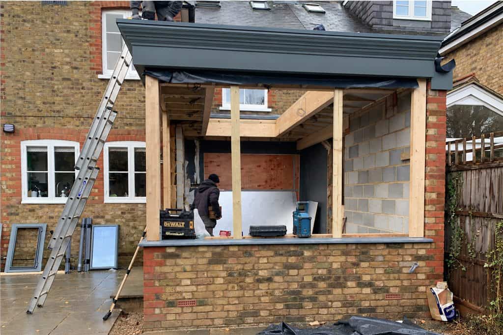 Part-built orangery with yellow stock brickwork, red brick corners and dark grey fascia