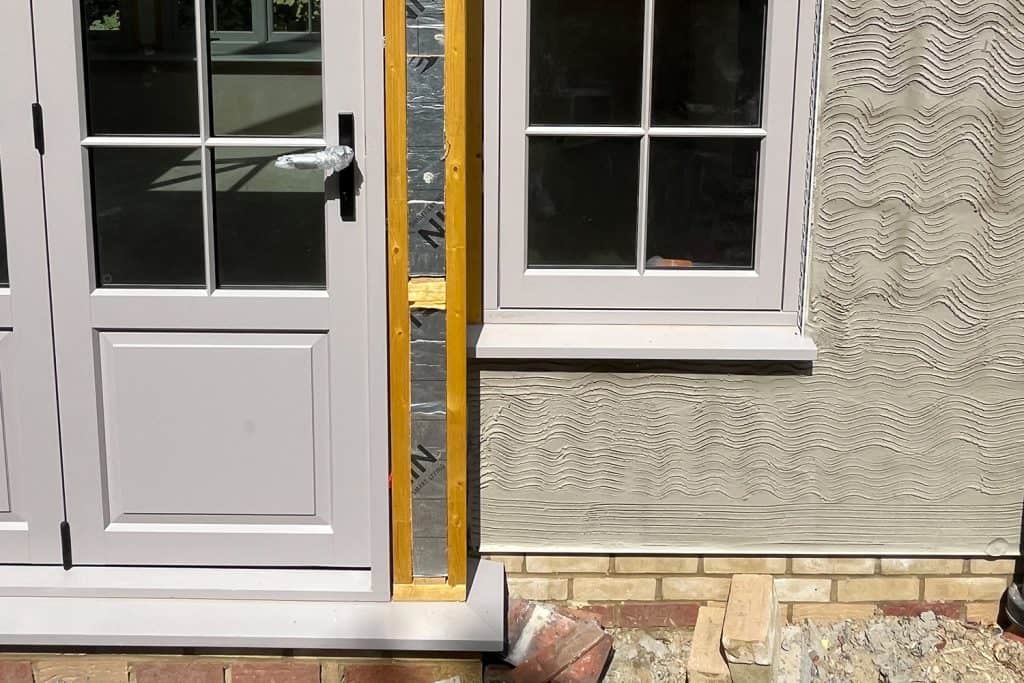 Scratch coat of render beside a newly fitted orangery door and window